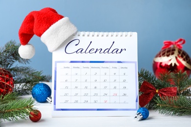 Photo of Flip calendar with Santa hat and Christmas decor on white wooden table. Holiday countdown