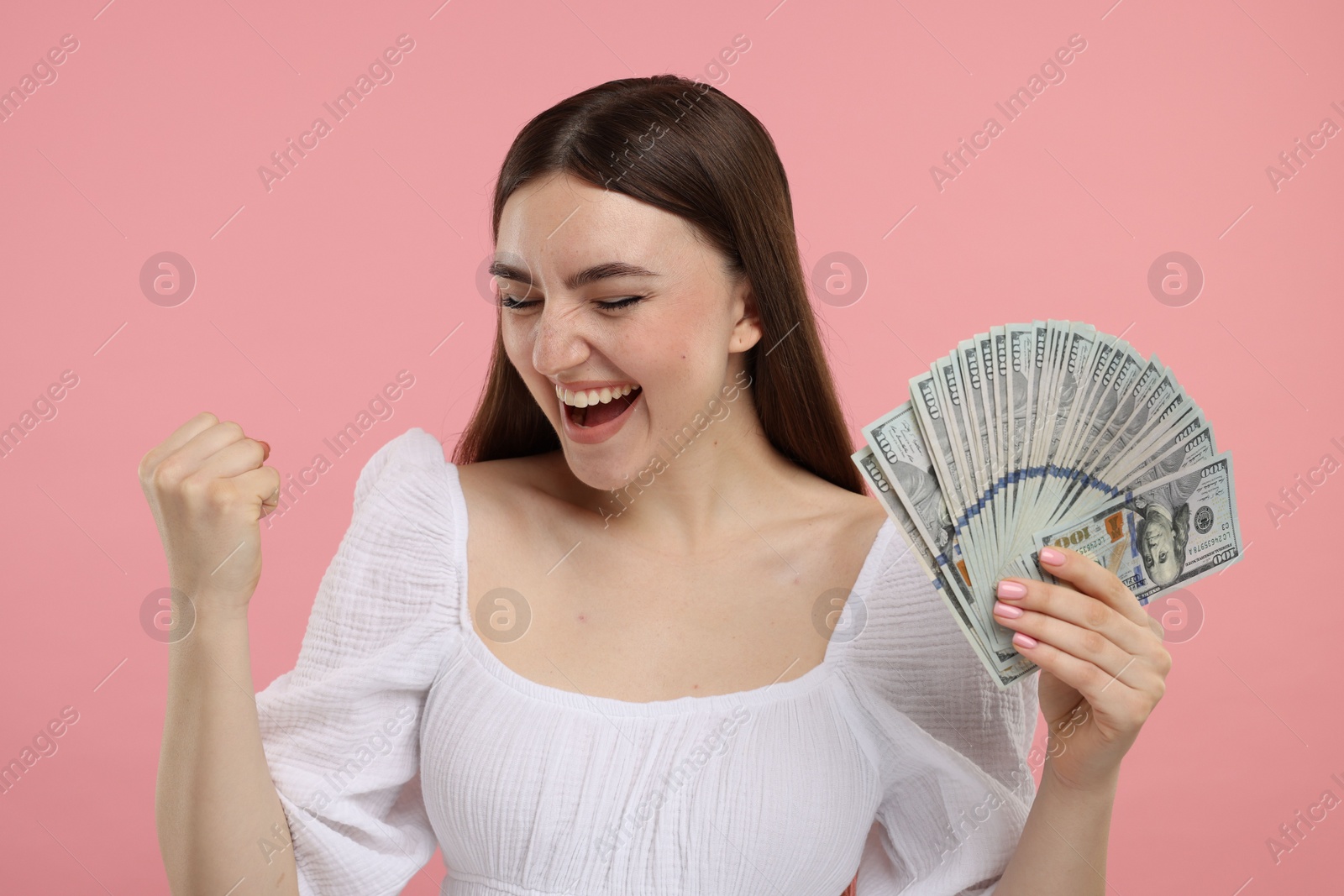 Photo of Excited woman with dollar banknotes on pink background