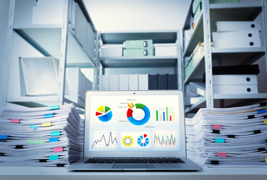 Image of Modern laptop and documents on desk in office. Business analytics