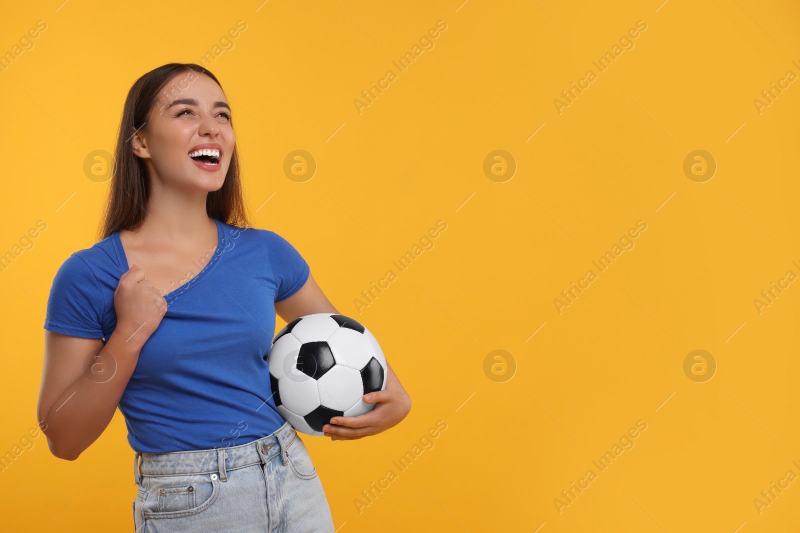 Photo of Happy fan holding soccer ball on yellow background, space for text