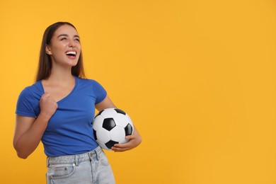 Photo of Happy fan holding soccer ball on yellow background, space for text