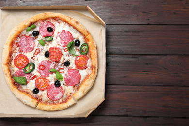 Photo of Delicious pizza Diablo in cardboard box on wooden background, top view. Space for text