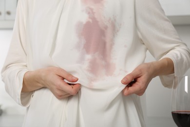 Woman with wine stain on her clothes indoors, closeup