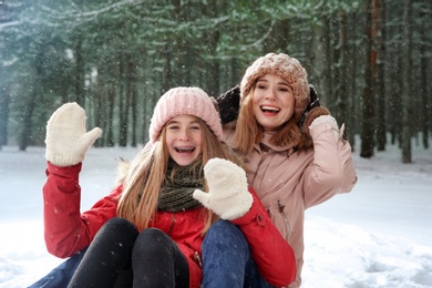 Mother and daughter having fun in forest on snow day