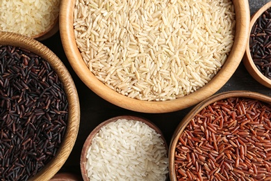 Photo of Flat lay composition with brown and other types of rice in bowls