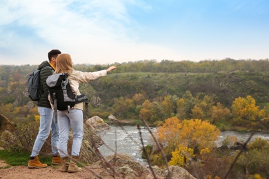 Couple of hikers with travel backpacks enjoying beautiful view near mountain river