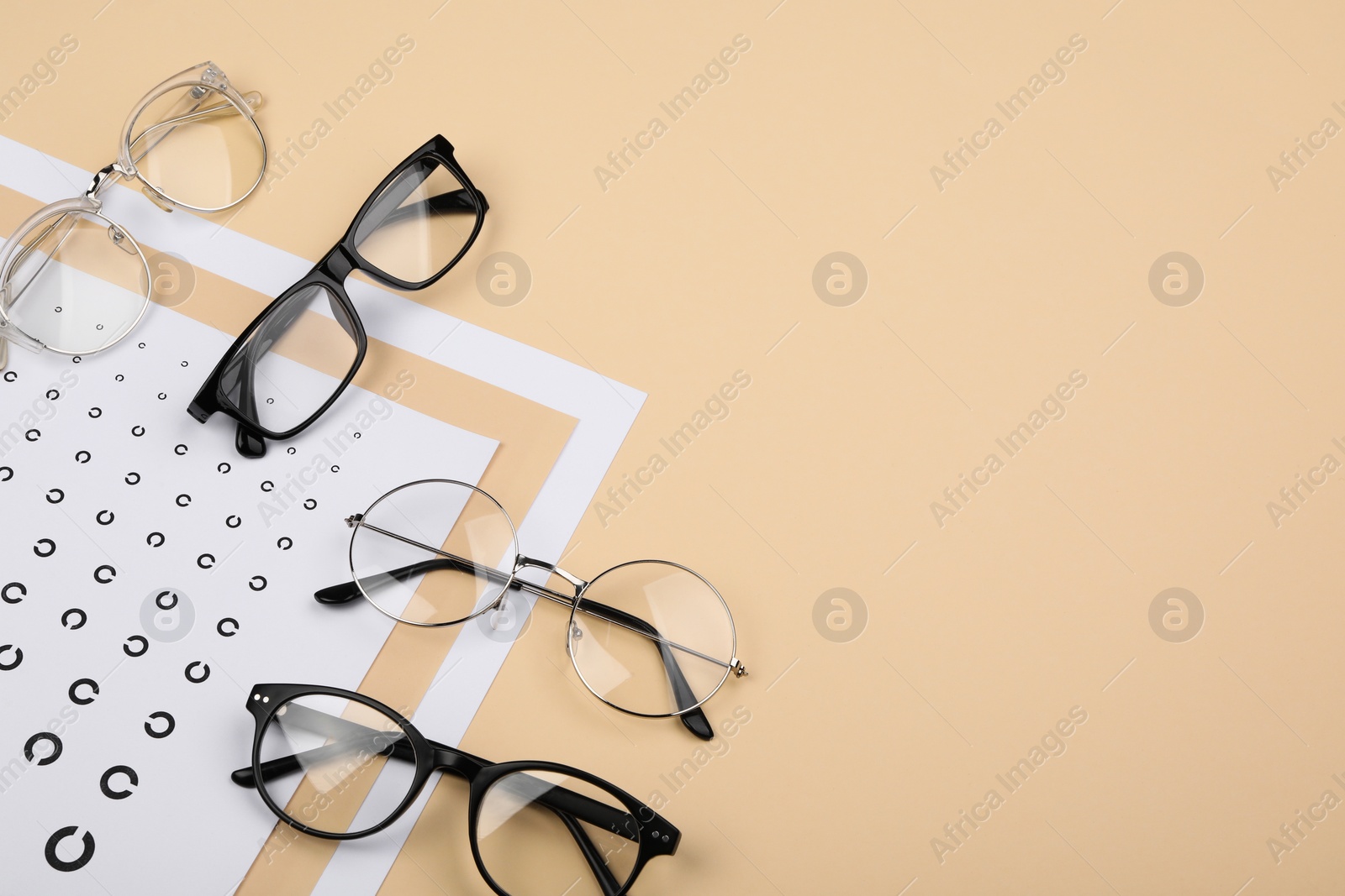 Photo of Vision test chart and glasses on beige background, flat lay. Space for text