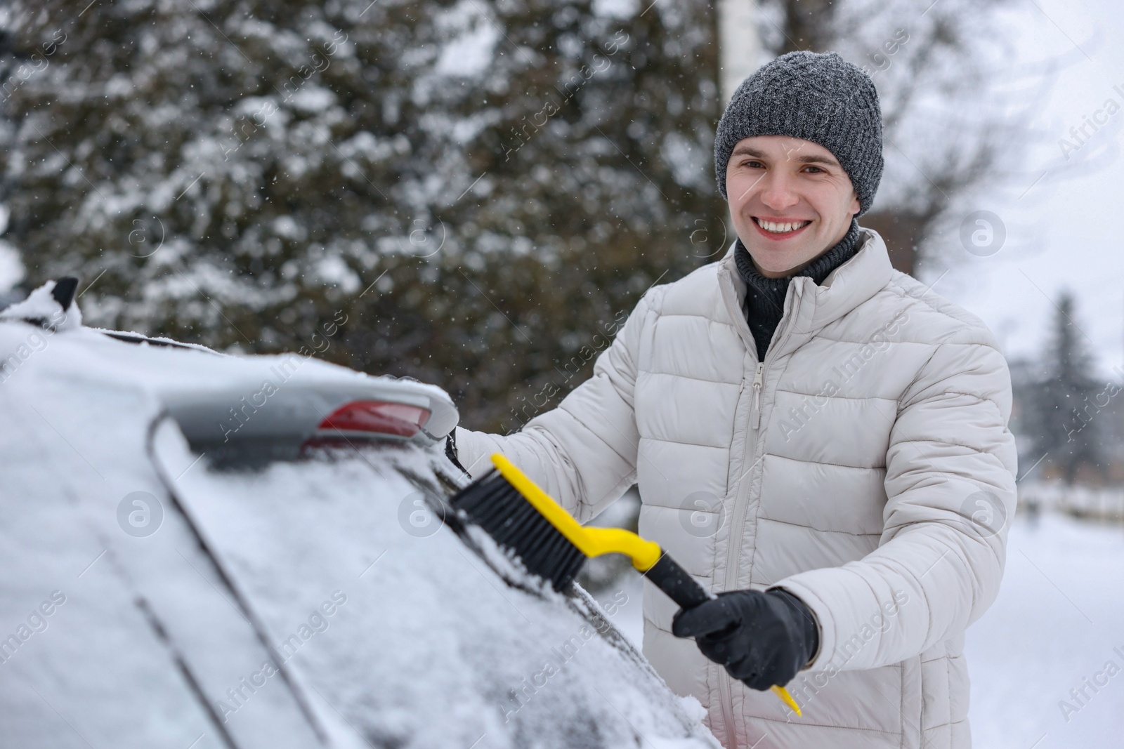 Photo of Man cleaning snow from car window outdoors