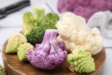 Photo of Various cauliflower cabbages on white table, closeup