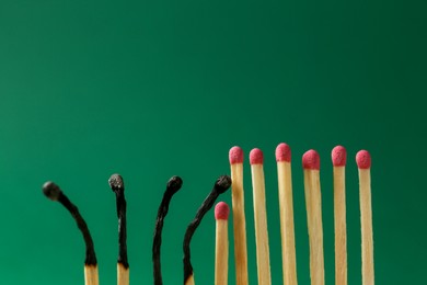 Photo of Burnt and whole matches on green background. Stop destruction concept