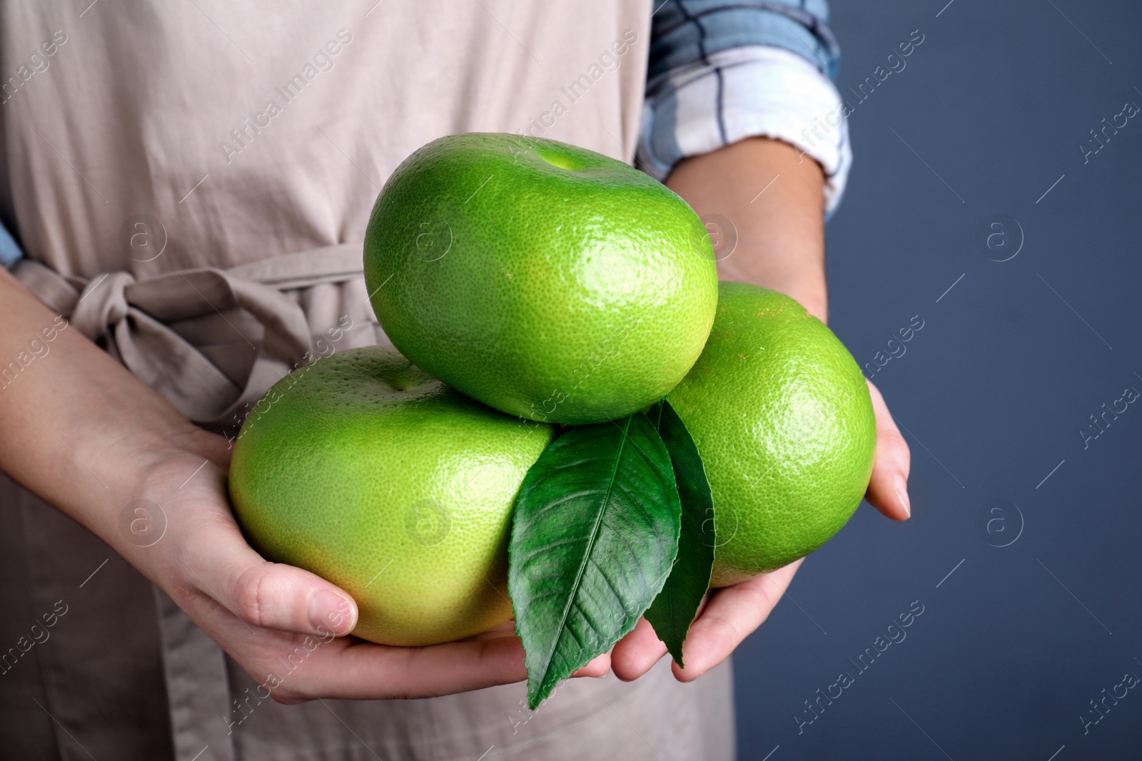 Photo of Woman holding sweetie fruits on blue background, closeup