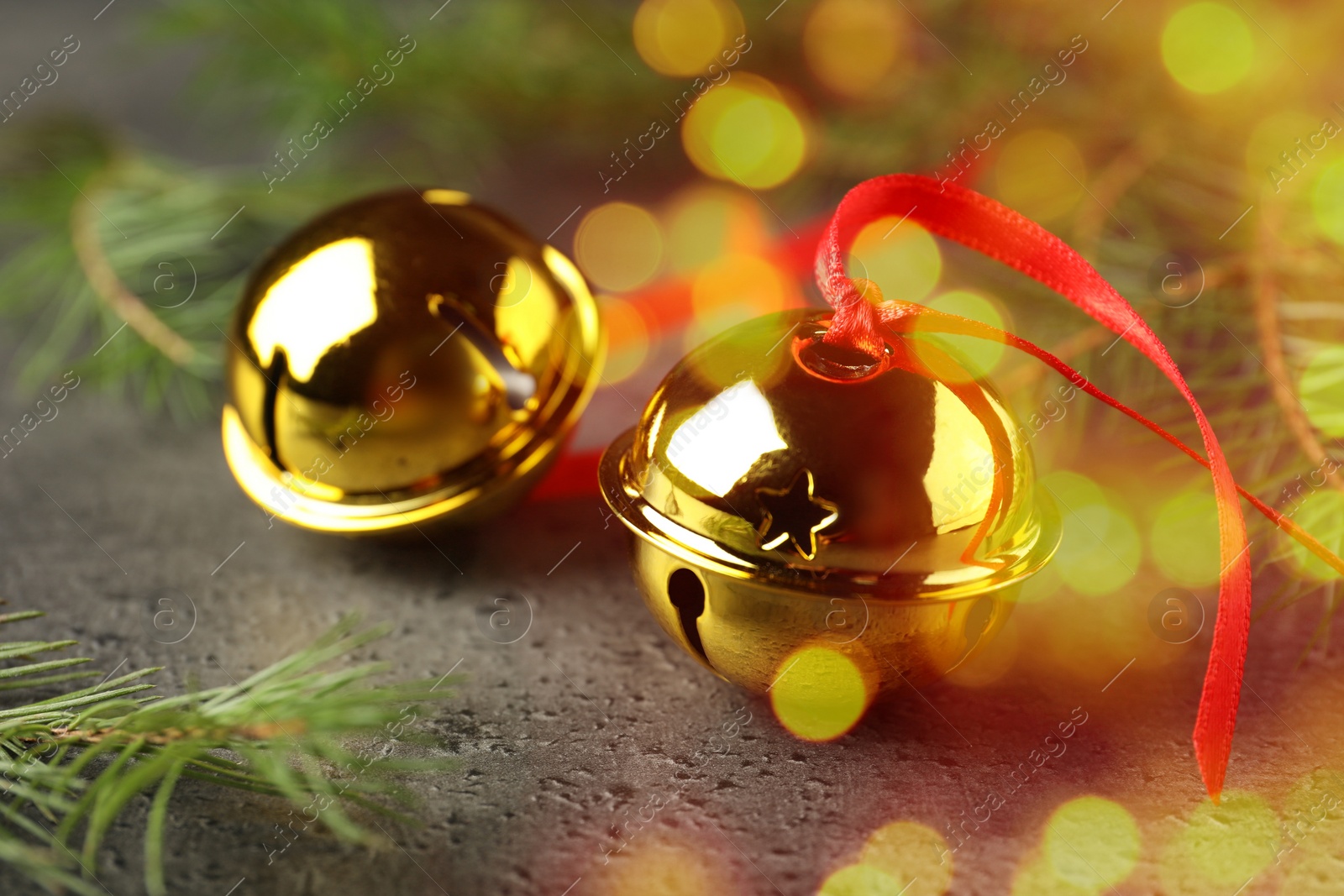 Image of Christmas music. Jingle bells and fir tree branch on grey table, bokeh effect