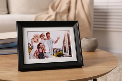 Frame with family photo on wooden coffee table in room, space for text
