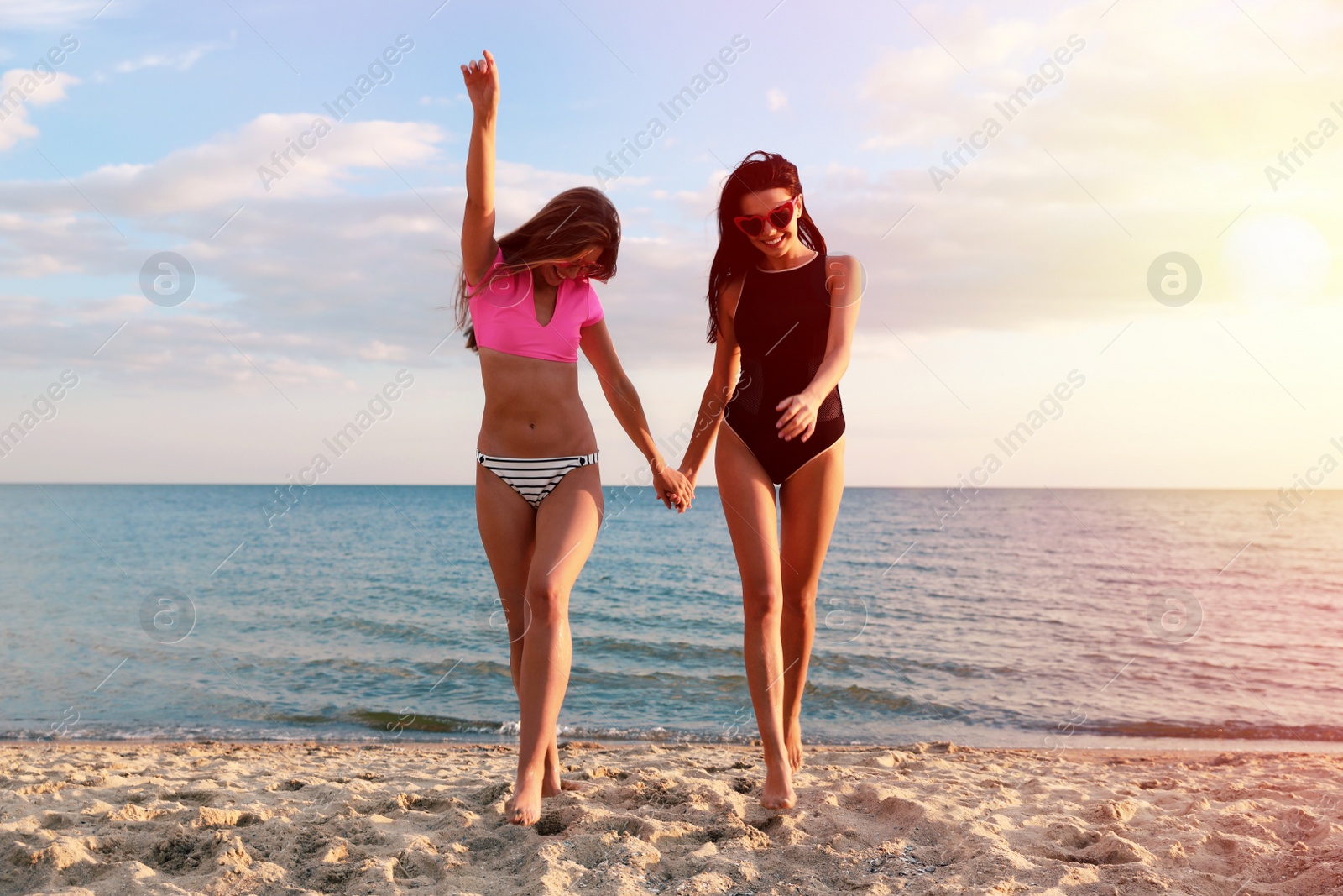 Photo of Young woman in bikini with girlfriend on beach. Lovely couple