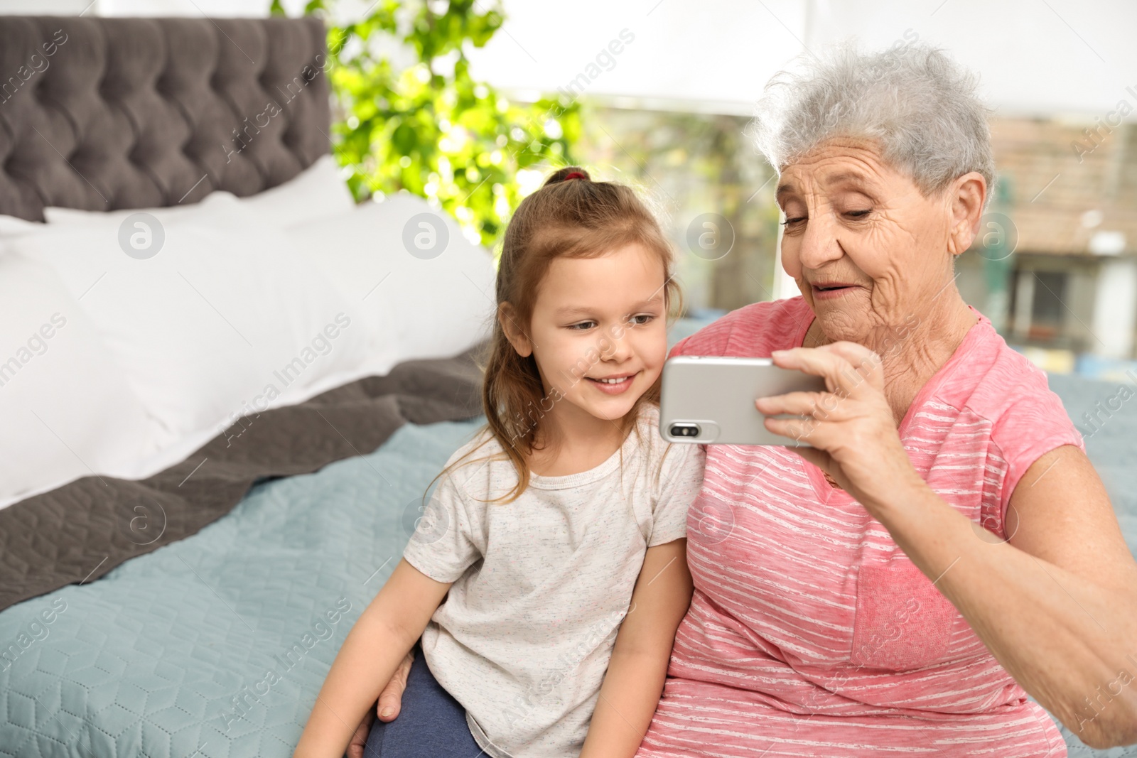 Photo of Cute girl and her grandmother taking selfie  at home