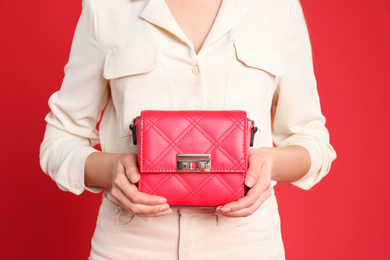 Photo of Young woman in casual outfit with stylish bag on red background, closeup