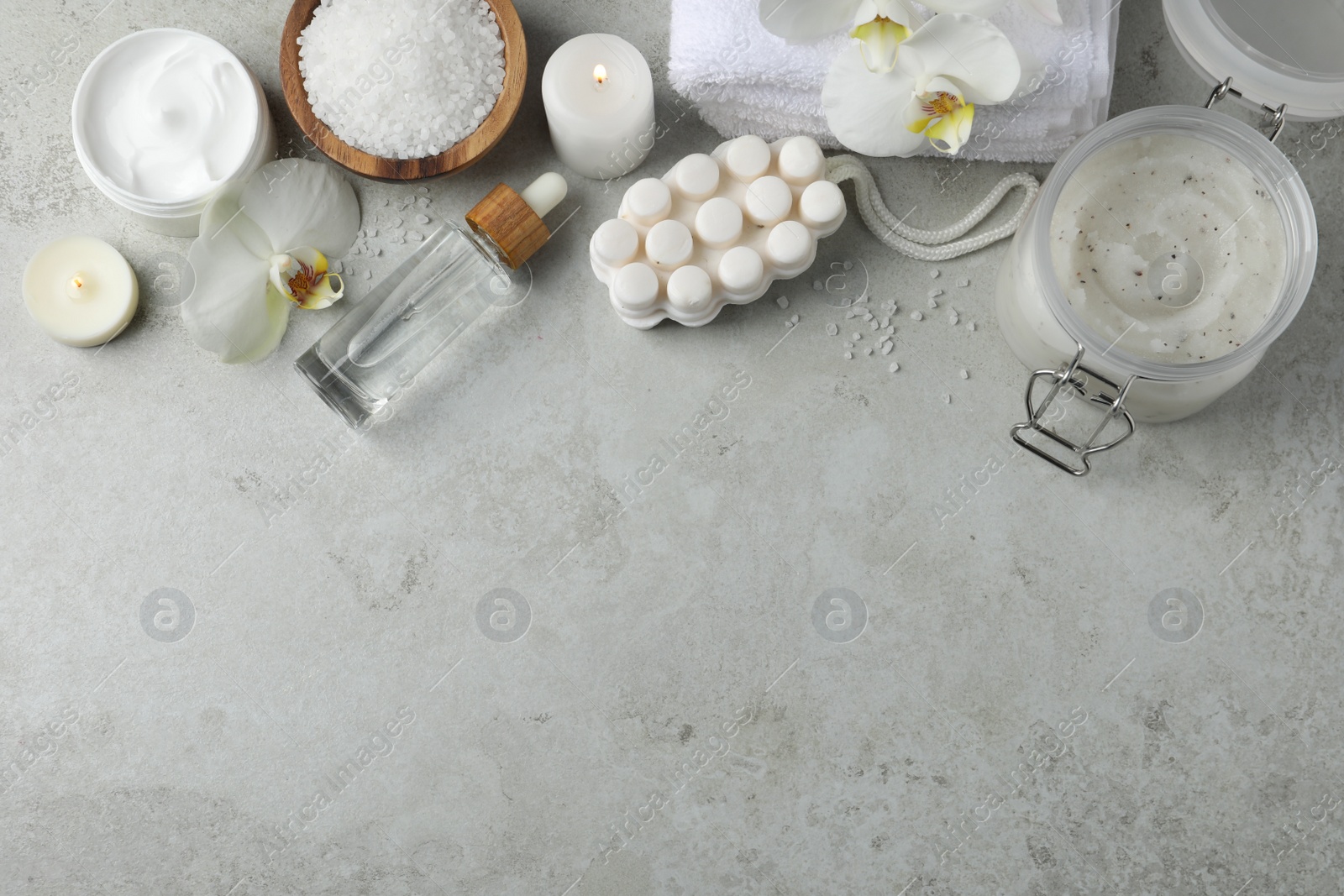 Photo of Flat lay composition with different spa products and burning candles on light grey table. Space for text