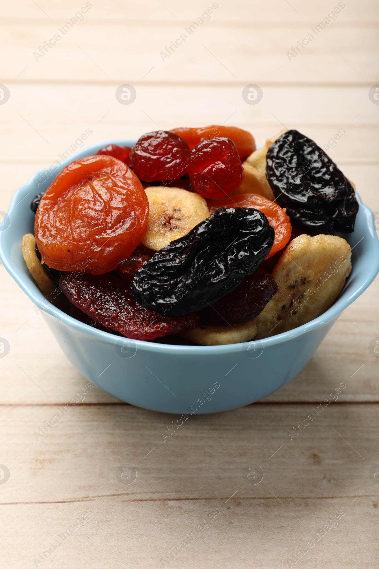 Photo of Mix of delicious dried fruits on white wooden table, closeup