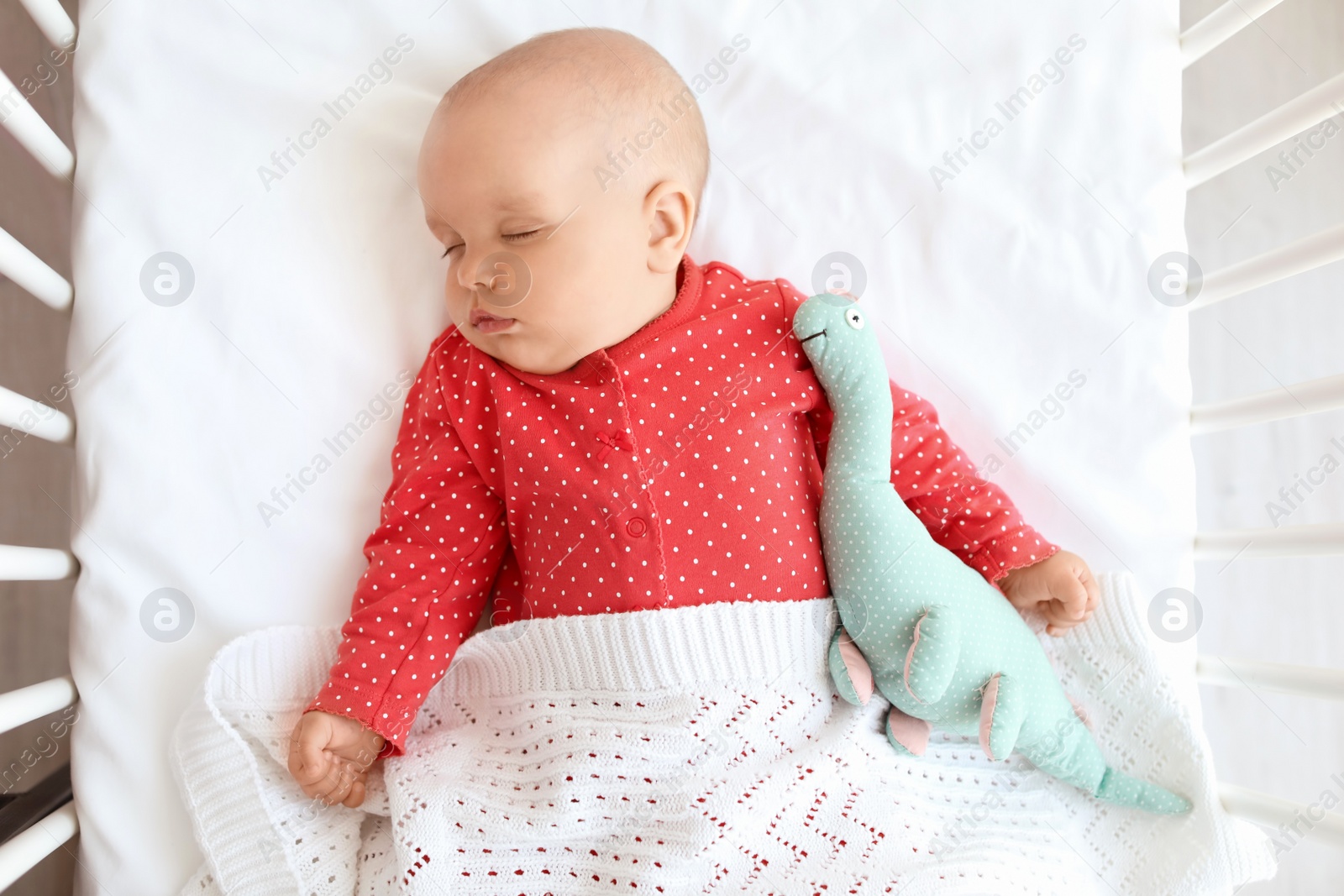 Photo of Cute baby girl sleeping in crib, top view