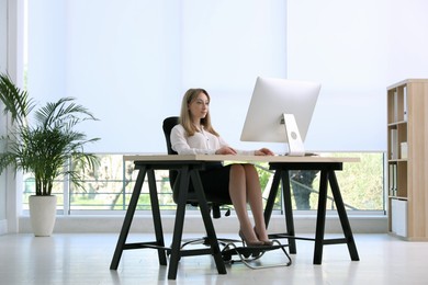 Photo of Woman using footrest while working on computer in office