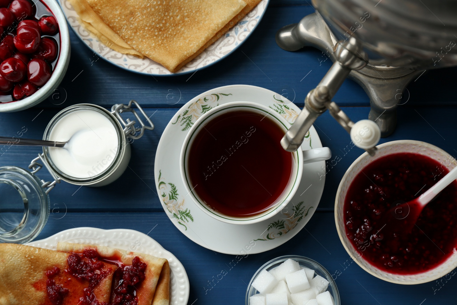 Photo of Aromatic tea, traditional Russian samovar and treats on light blue wooden table, flat lay