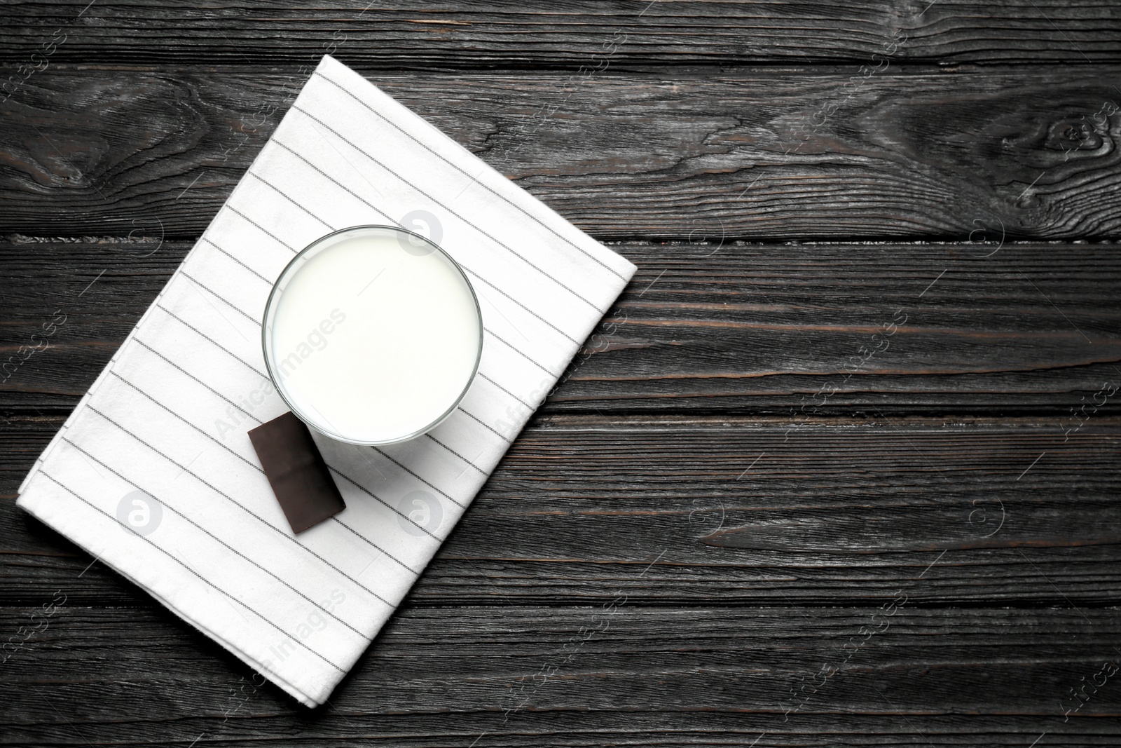 Photo of Glass of milk and chocolate piece on wooden background