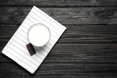 Glass of milk and chocolate piece on wooden background