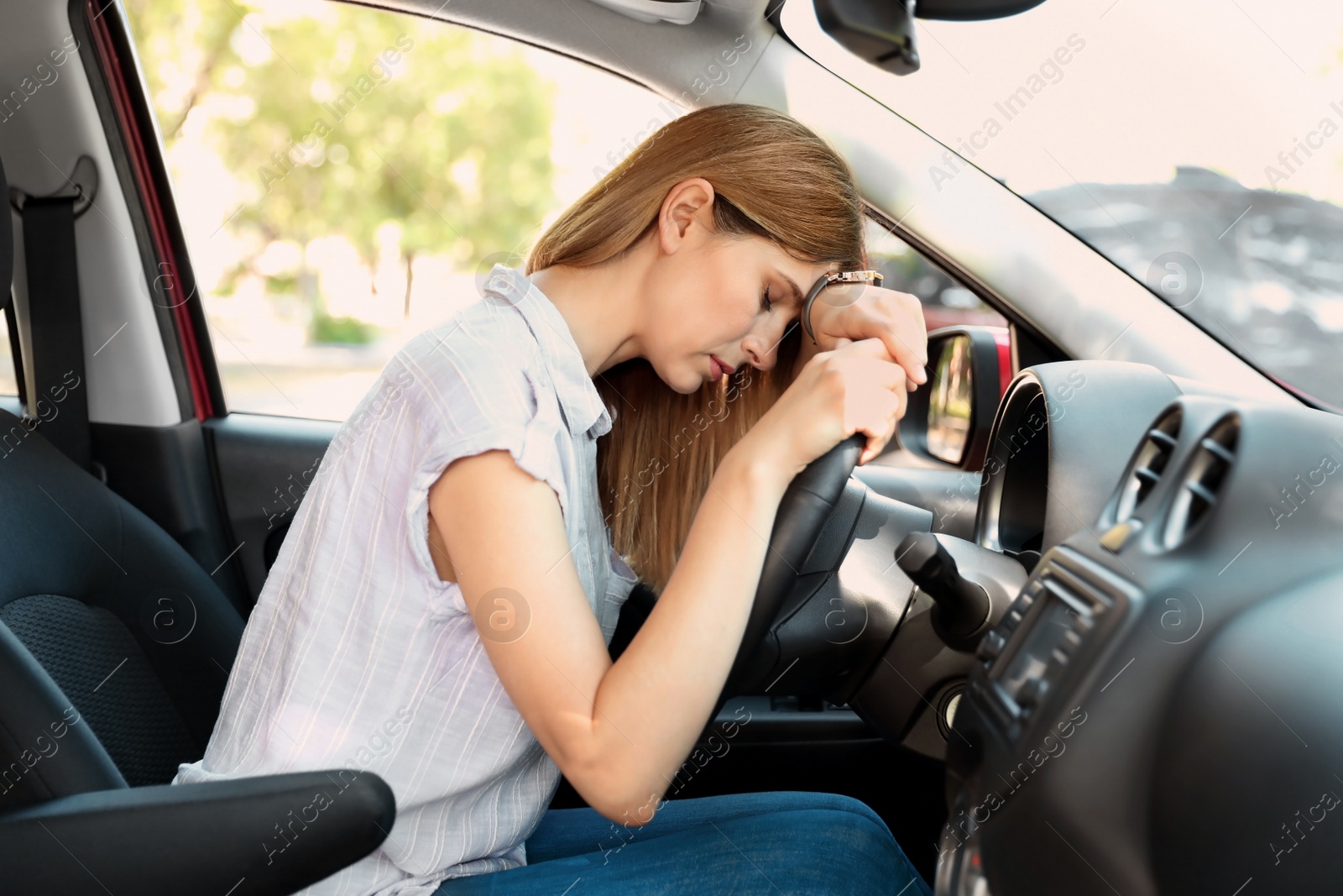 Photo of Tired woman sleeping on steering wheel in car