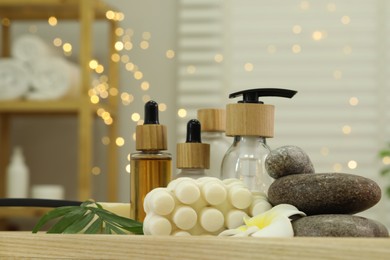 Composition with different spa products and plumeria flower on tray in bathroom