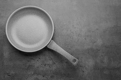 Photo of New non-stick frying pan on grey table, top view. Space for text