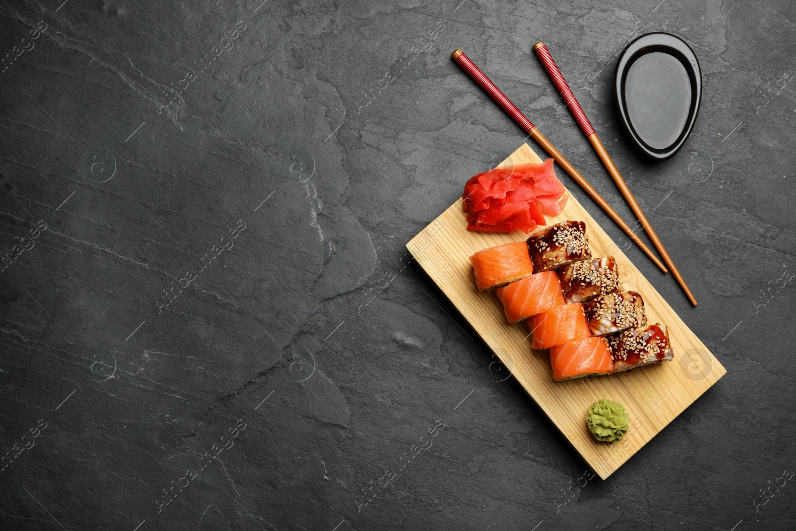 Photo of Delicious sushi rolls on dark grey table, flat lay. Space for text