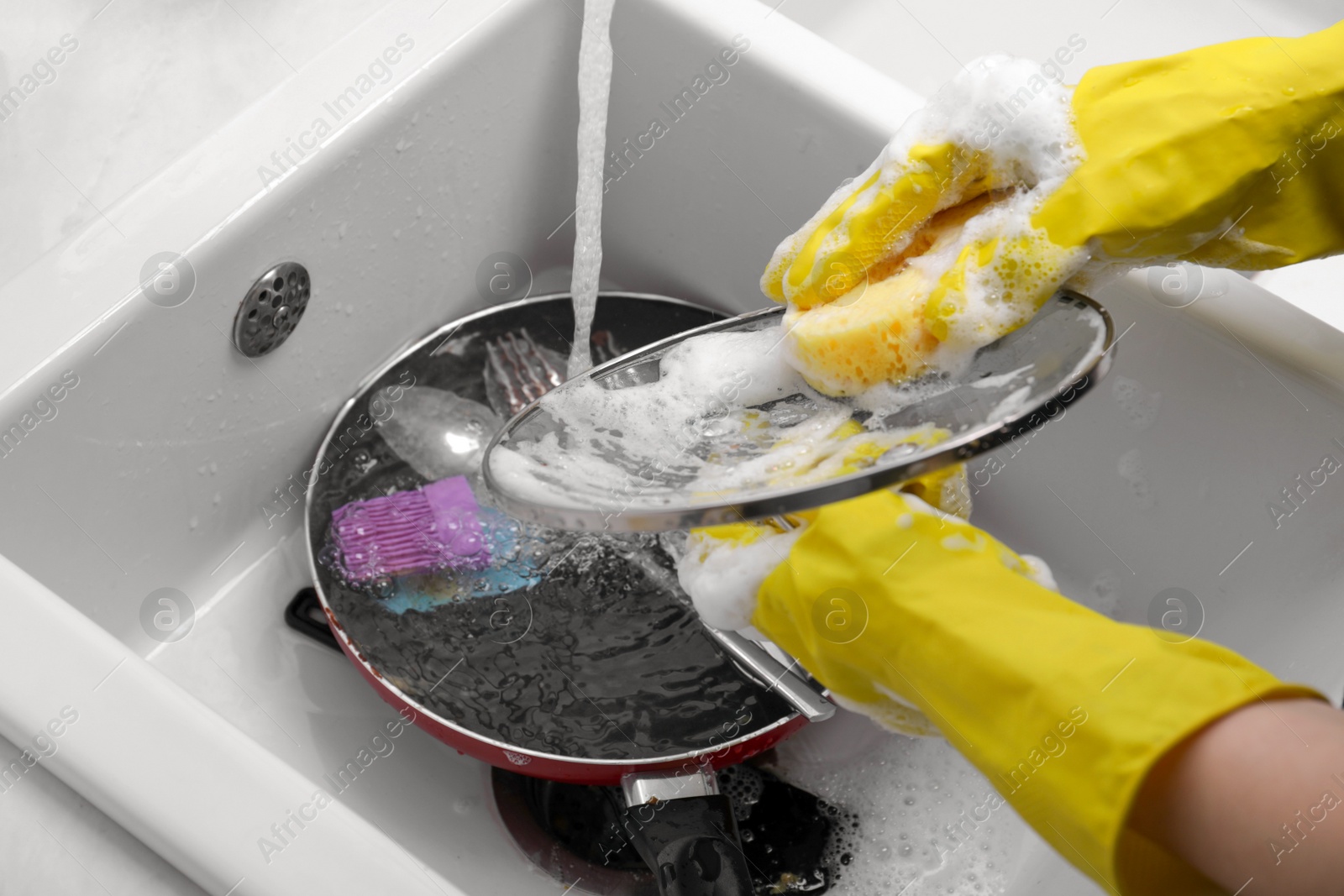 Photo of Woman washing dirty dishes in kitchen sink, closeup