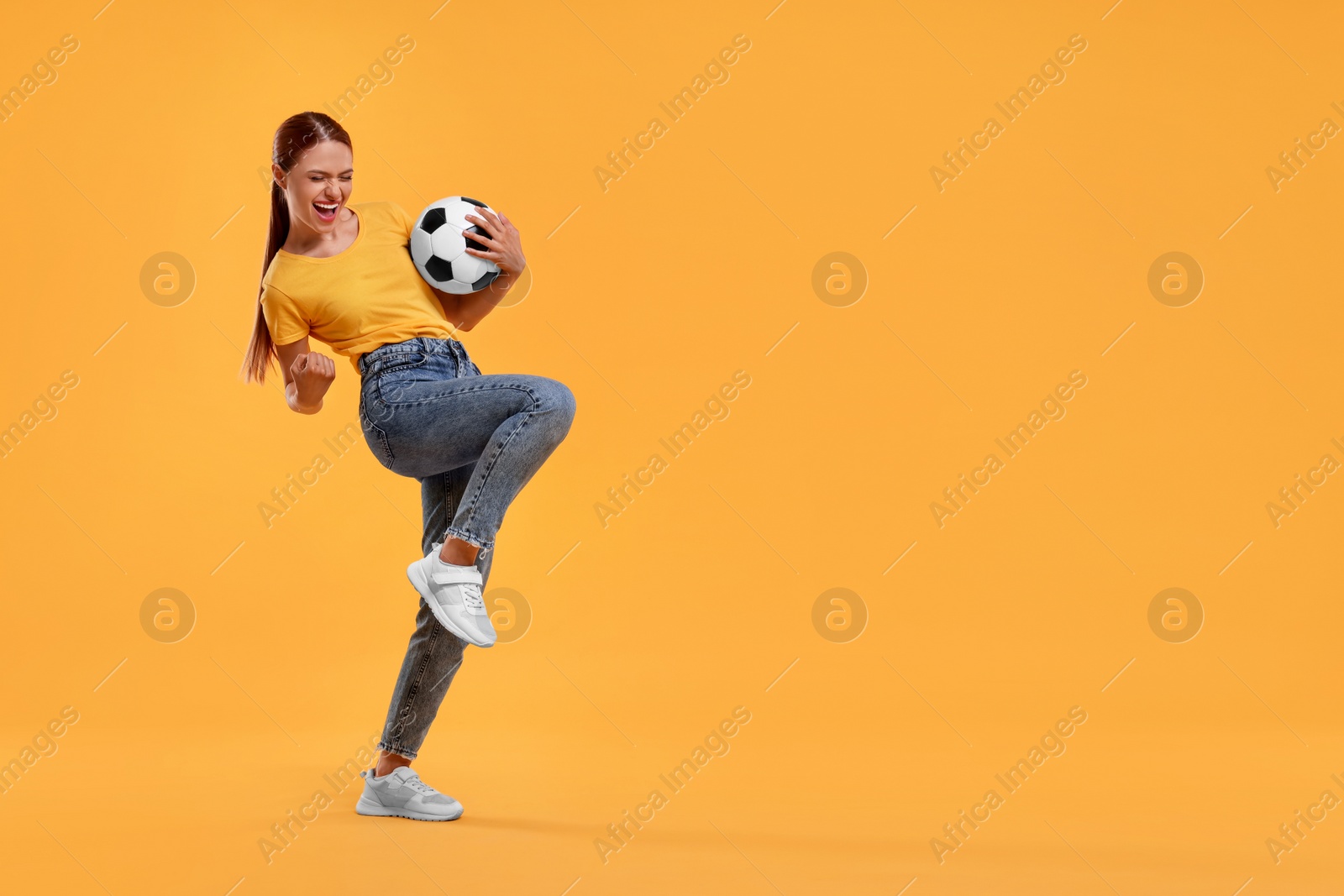 Photo of Happy fan with football ball celebrating on yellow background, space for text