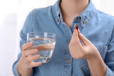 Photo of Young woman with pill and glass of water, closeup
