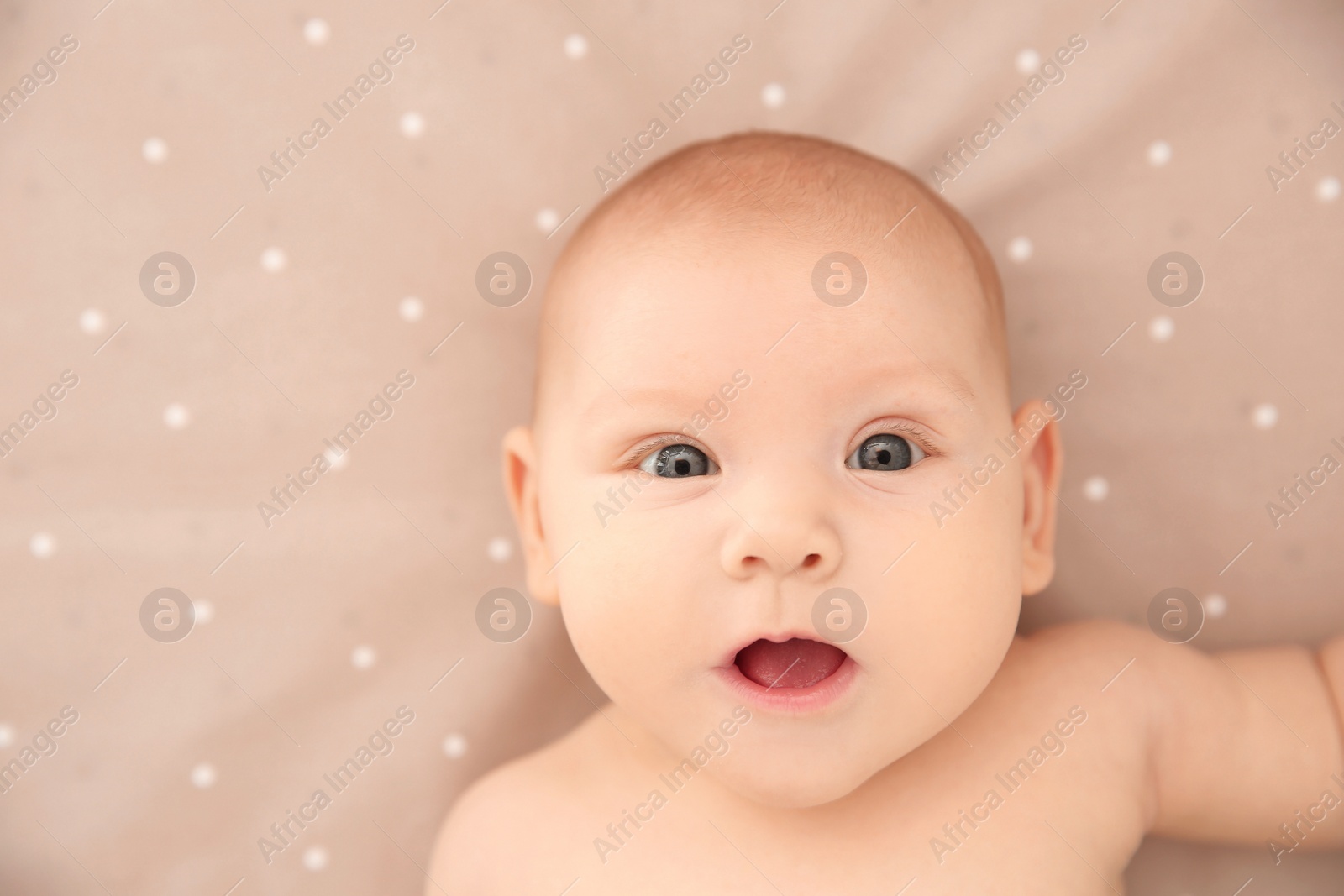 Photo of Adorable baby girl lying on bed, top view