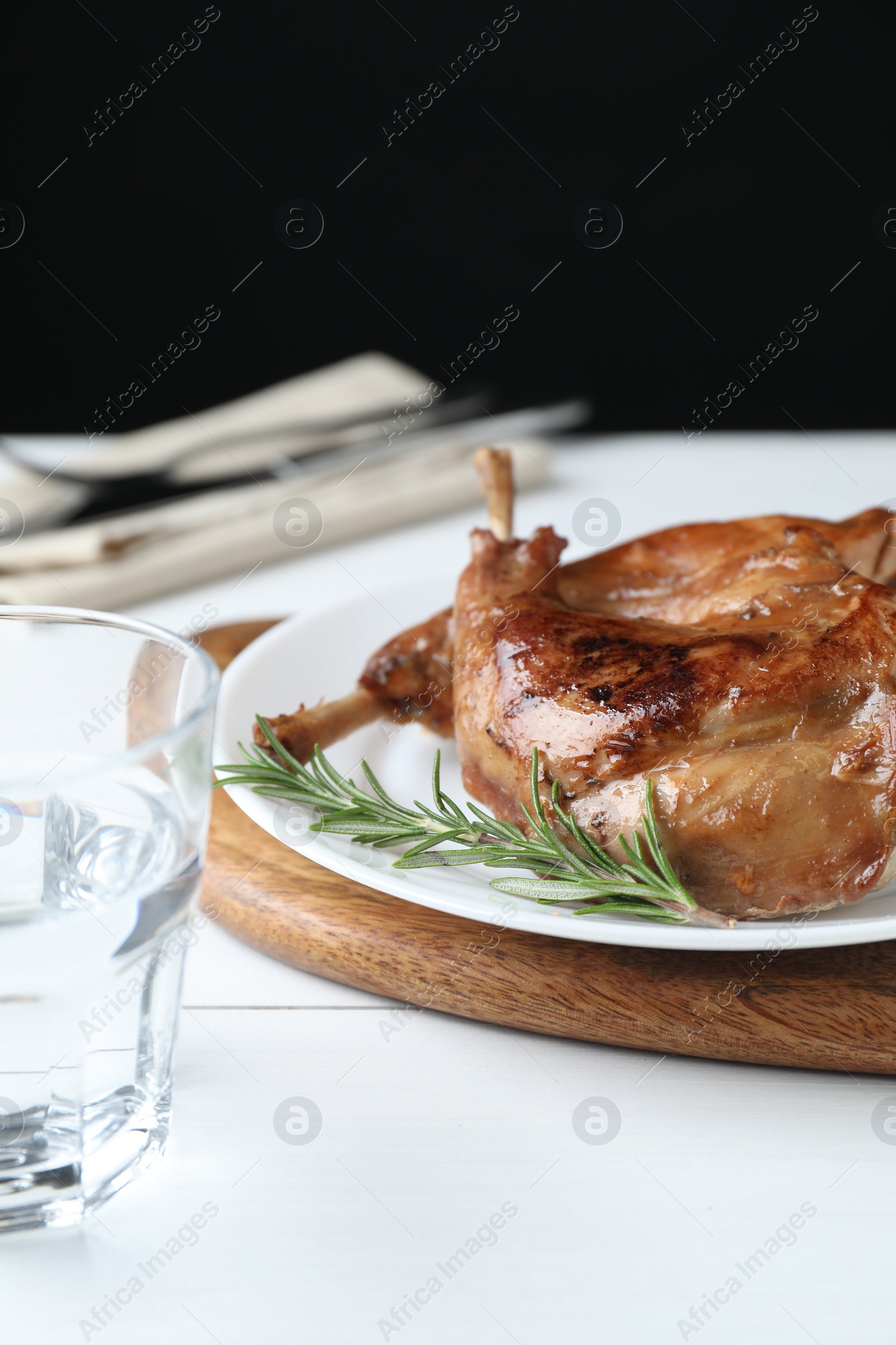 Photo of Tasty cooked rabbit meat with rosemary on white wooden table