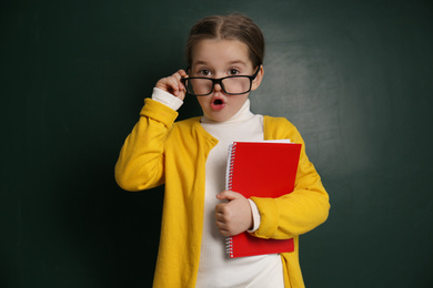 Cute little child wearing glasses near chalkboard. First time at school