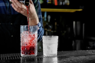 Barman making Red Russian cocktail at counter in pub, closeup. Space for text