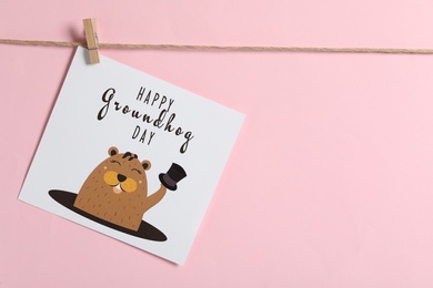 Happy Groundhog Day greeting card hanging on pink background, space for text