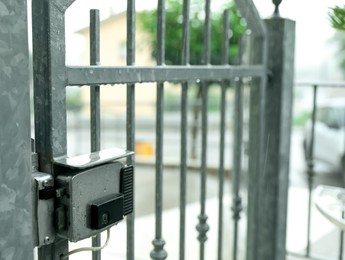 Photo of Stainless electromechanical lock on gate outdoors under rain