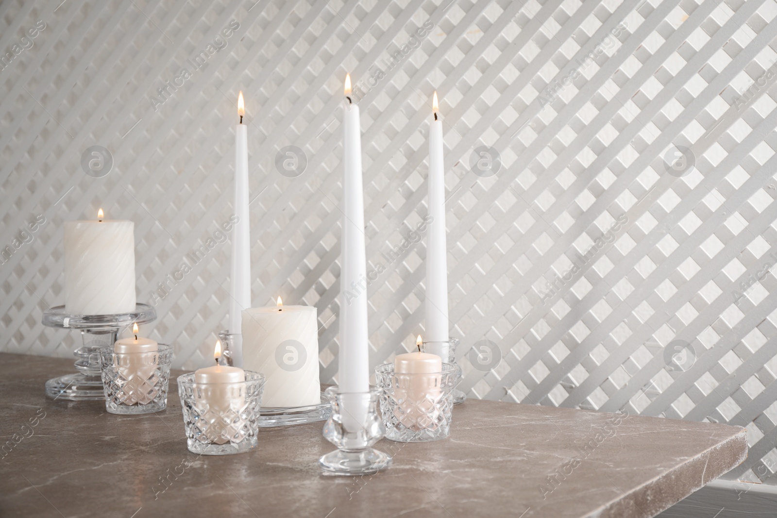 Photo of Elegant candlesticks with burning candles on marble table