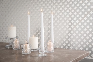 Elegant candlesticks with burning candles on marble table