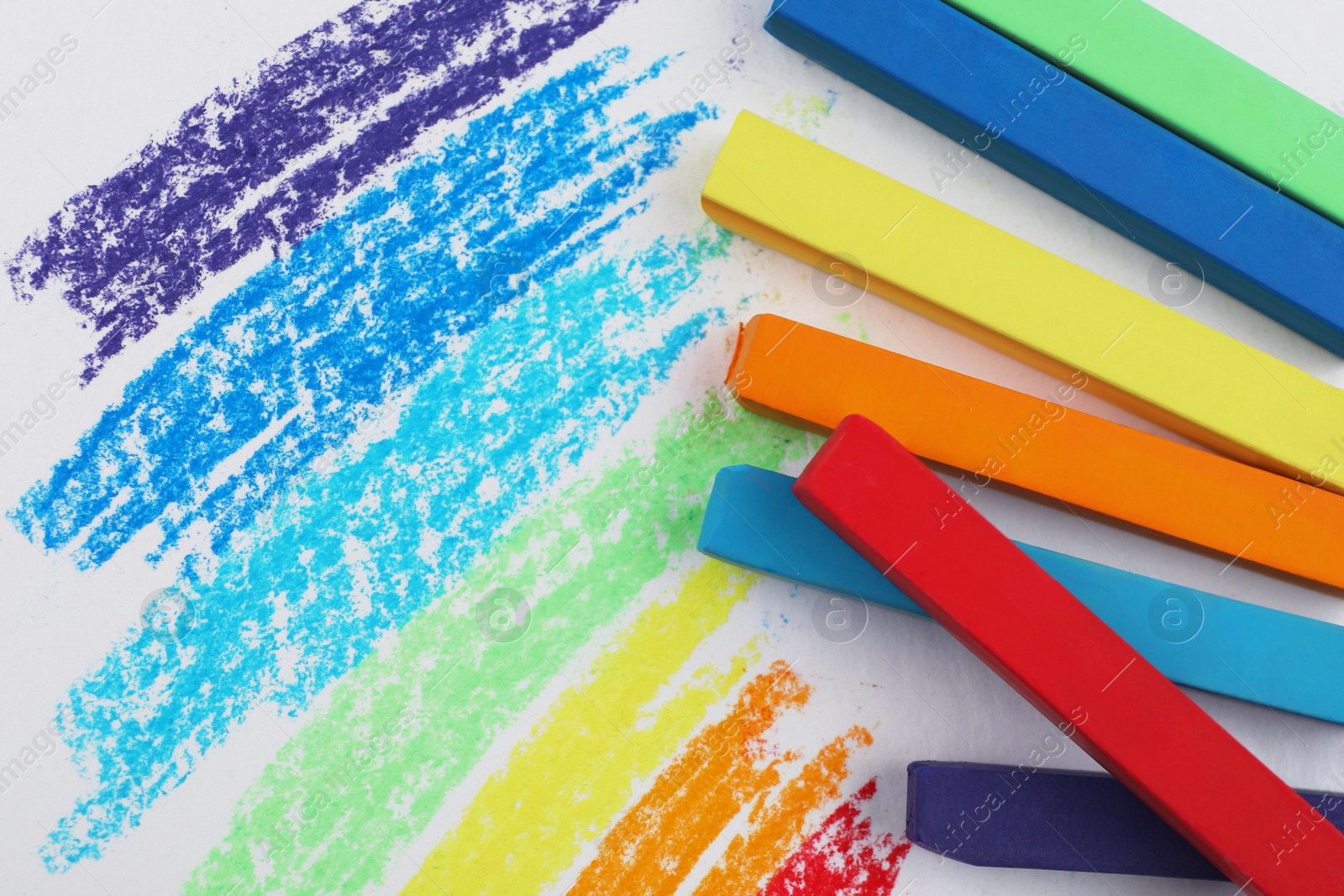 Photo of Colorful pastel chalks and scribbles on white background, flat lay. Drawing materials