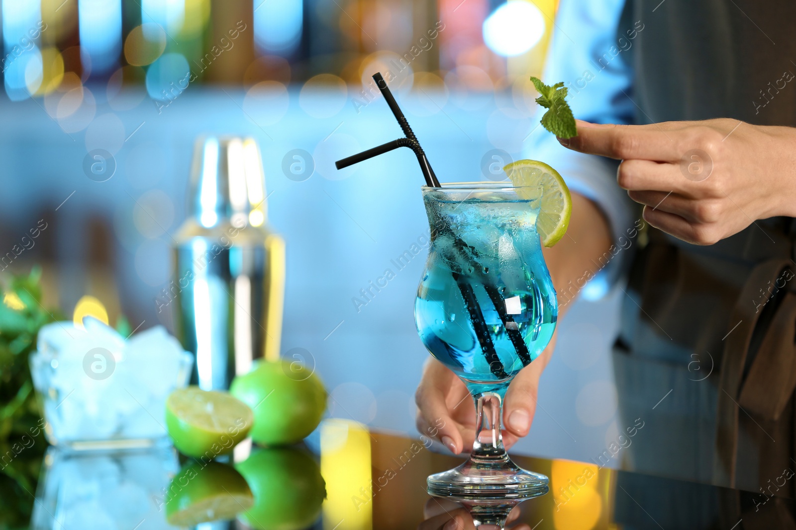 Photo of Bartender decorating glass of fresh alcoholic cocktail at bar counter