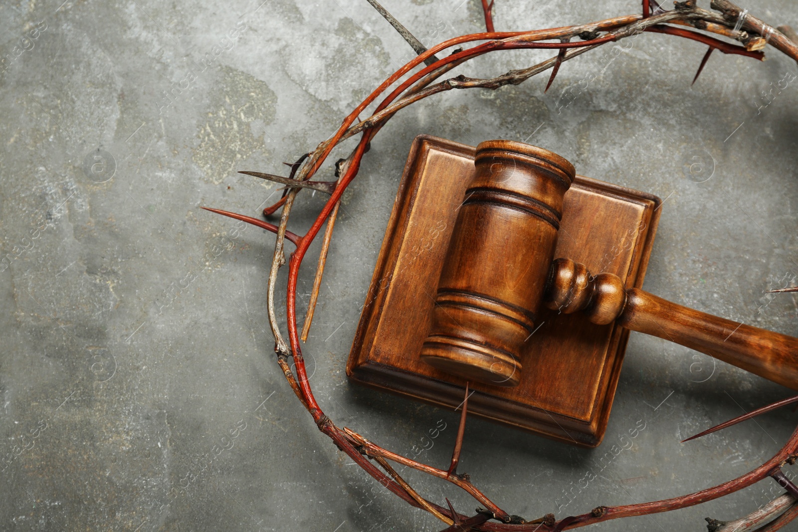 Photo of Crown of thorns and judge gavel on grey table, flat lay. Space for text