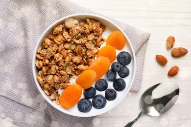 Delicious granola with fruits on white wooden table, flat lay