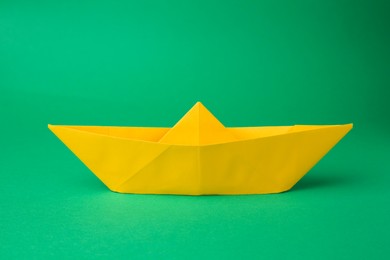 Photo of Origami art. Yellow paper boat on green background