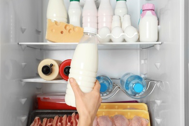 Woman taking bottle of milk from refrigerator, closeup