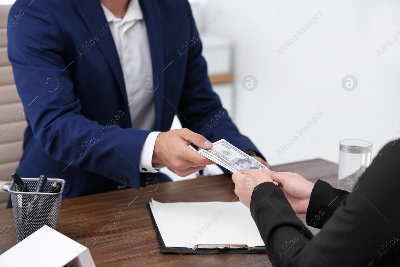 Photo of Woman giving bribe money to man at table, closeup