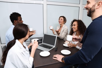 Photo of Team of employees enjoying coffee break together in office. Startup project